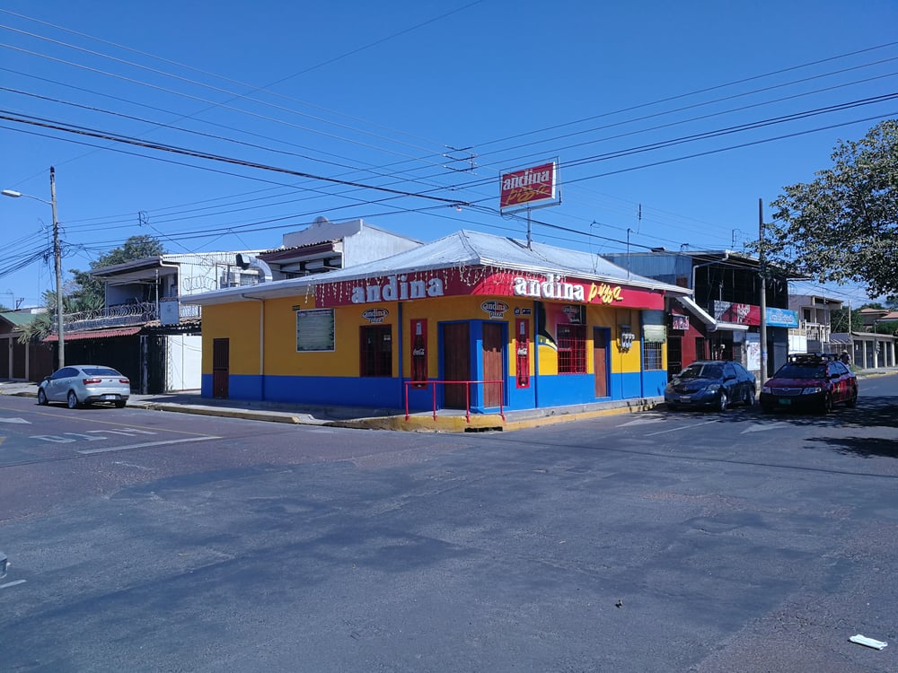 Kruispunt met auto's en kleurrijk cafe in Costa Rica