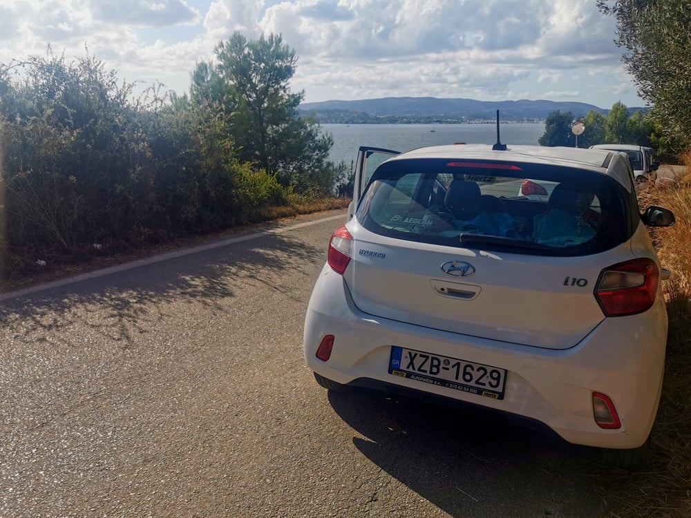Een witte auto geparkeerd bij de zee in Griekenland