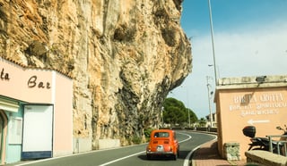 Een rode auto op een Italiaans weggetje